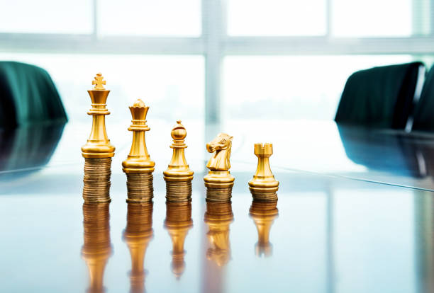istock Chess pieces standing on the stacked coins 957612642