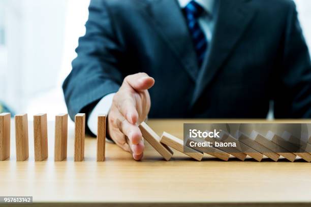 Businessman Hand Stopping Falling Blocks On Table Stock Photo - Download Image Now - Domino Effect, Domino, Falling