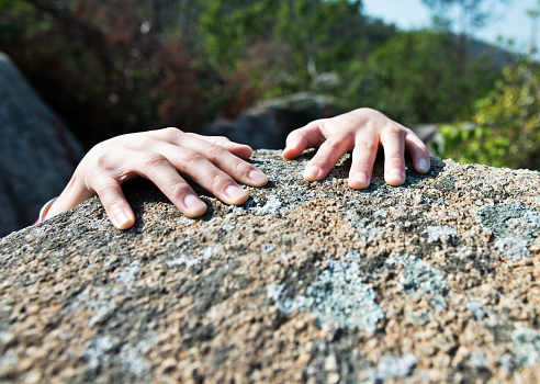 Woman hand at the edge of the rock.