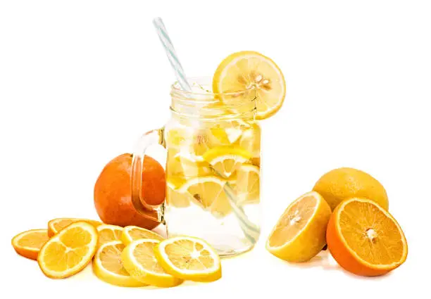 Photo of lemonade in a mason jar with a drinking straw decorated with slices of lemon and orange isolated on white background