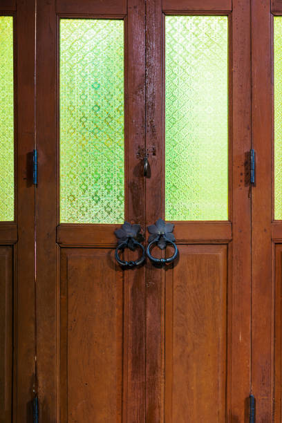 istock Folding wooden doors with black handles and green pattern glass 957624024