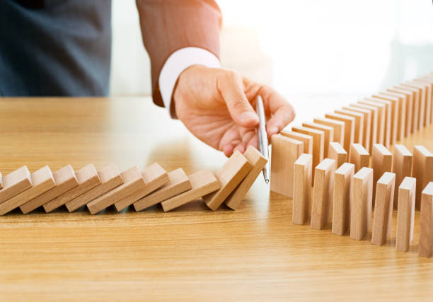 istock Businessman hand holding a pen stop domino effect 957624758