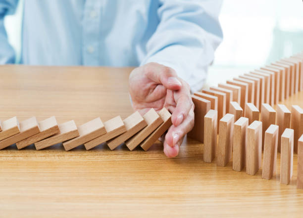 istock Businessman hand stopping falling blocks on table 957624840