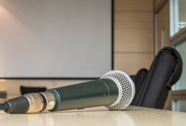 istock Microphone on wood desk in meeting room under window light 957624980