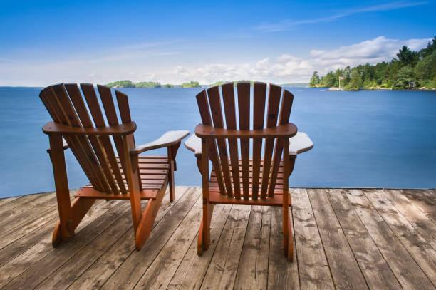 istock Two Adirondack chairs sitting on a wooden dock 957632562