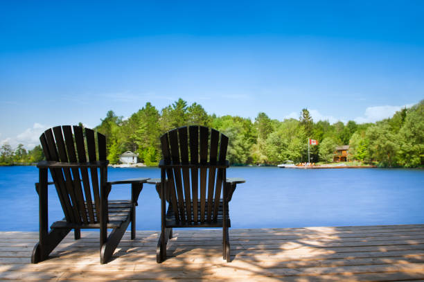istock Adirondack chairs sitting on a wooden dock 957632610