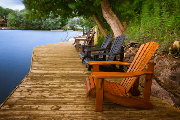 istock Multiple Adirondack chairs sitting on a wooden dock 957633146