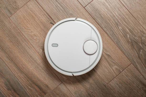 istock Robot vacuum cleaner cleaning dust on tile floors. Modern smart cleaning technology housekeeping. Top view 957642024