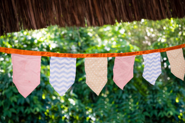 istock Decorative triangular and square party flags and lamps on trees, toned and with various patterns, with blurry green background 957646778