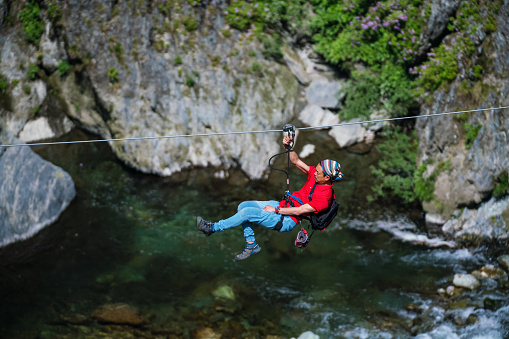 Man on a zip line flying through a forested canyon