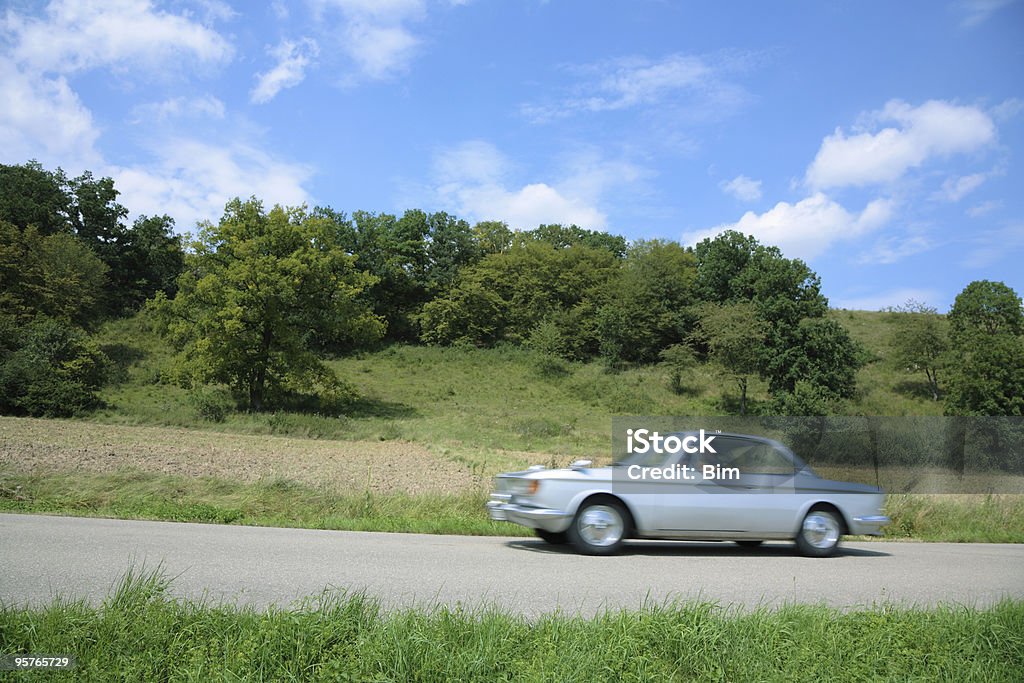 Vintage auto guida attraverso un paesaggio estivo - Foto stock royalty-free di Automobile