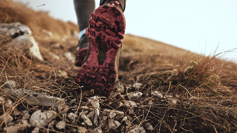 Slow motion low angle close up shot of the feet of a female runner running uphill pushing gravel and dirt into the air. Shot in Slovenia.