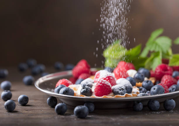 Tarts with raspberries, strawberries and bilberries on wooden plank