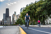 Young man cycling in Chicago by Michigan lake, commuting to work