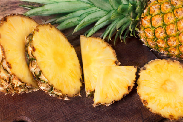 istock pineapple slices on wooden background 957673600