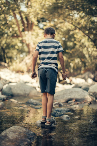 istock Little boy crossing over creek 957676416