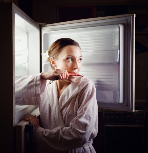 istock Young woman looking for some snack in fridge late at night 957679616