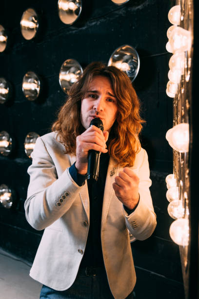 istock men singer with long hair, with microphone on the stage 957686268