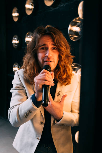 istock men singer with long hair, with microphone on the stage 957686358