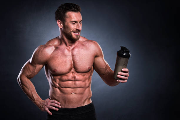 Male fitness athlete Studio shot of male fitness athlete while holding a protein shaker bottle. bodybuilding supplement stock pictures, royalty-free photos & images