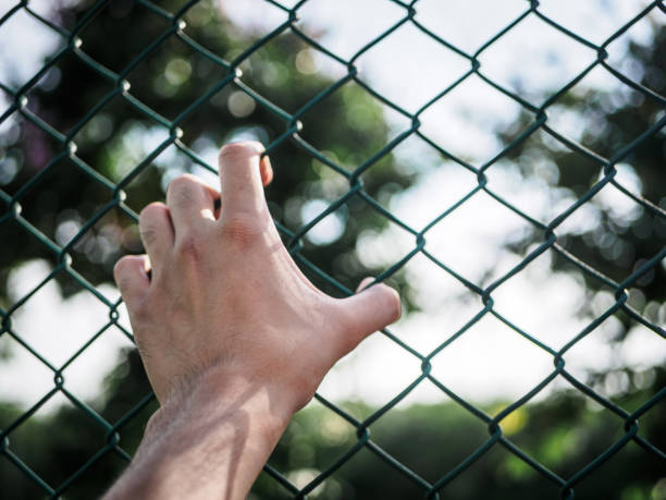 istock Man hand holding on chain link fence to remember Human Rights Day concept. 957689982