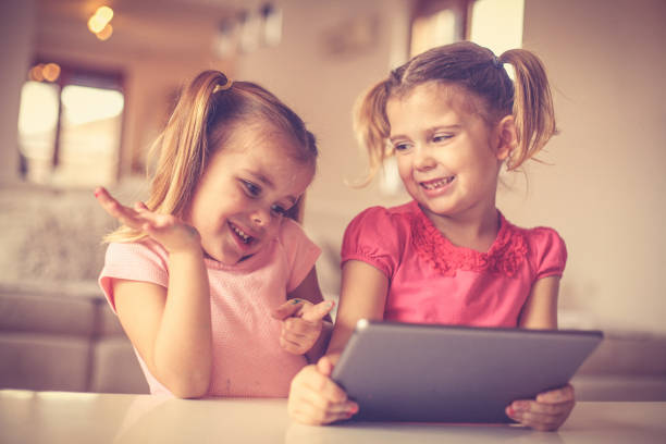 istock Cute little girls playing on digital tab. 957690302