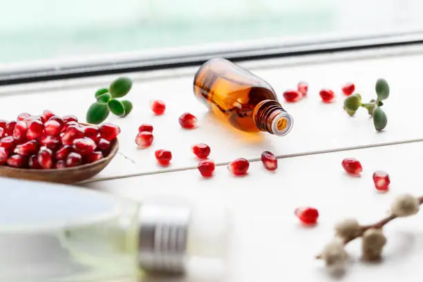 Natural product garnet oil in a glass bottle on a light background.