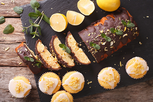 Sliced lemon cake with chocolate and lemon muffins with icing and zest close-up on the table. horizontal view from above