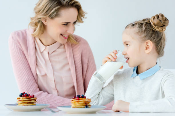 istock happy mother and daughter having breakfast together at table 957699056