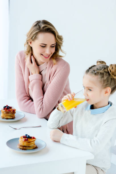istock happy mother and daughter having breakfast together at table 957699944