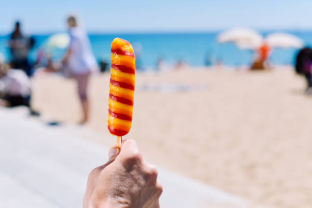 istock man eating a popsicle on the beach 957703634