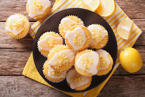 Sweet lemon muffins with zest and icing sugar close-up on a plate on the table.  Horizontal view from above