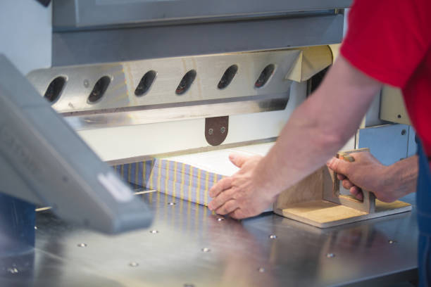 manos de trabajador trabajo con cortador de guillotina máquina en una fábrica de la impresión - print shop fotografías e imágenes de stock