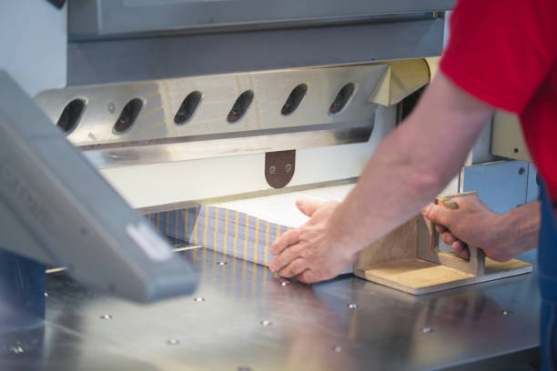 ręce pracownika pracującego na maszynie gilotyny tnącej w drukarni - print shop zdjęcia i obrazy z banku zdjęć
