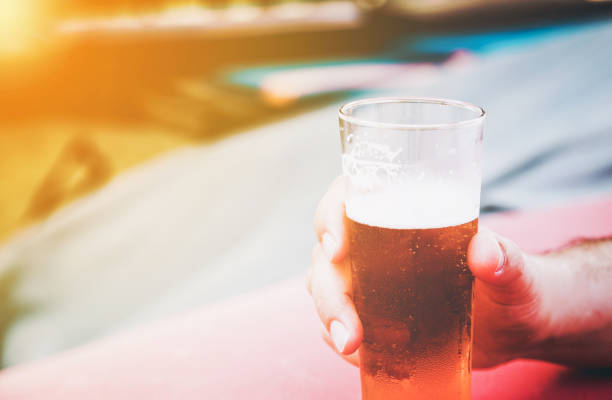 Male hand holding a small glass of cold beer stock photo