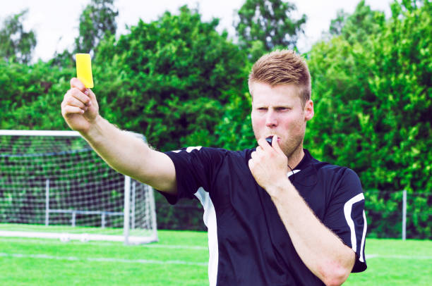 istock Sports referee blows whistle and shows yellow card 957708100