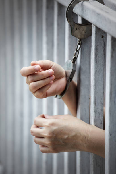 istock close up of prisoner hands in jail background. 957709142
