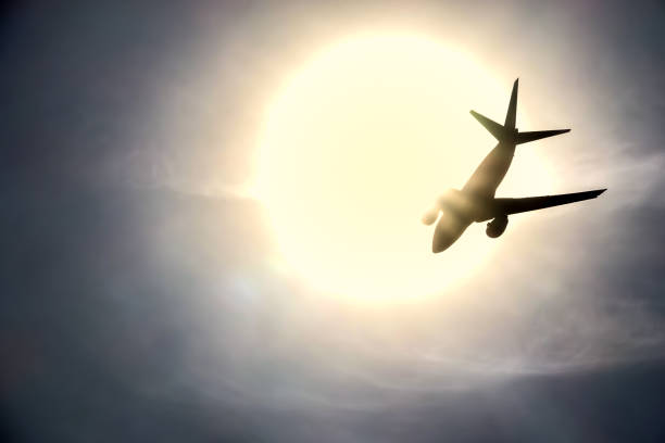 istock Silhouette of a jet plane flying into the sun 957710112