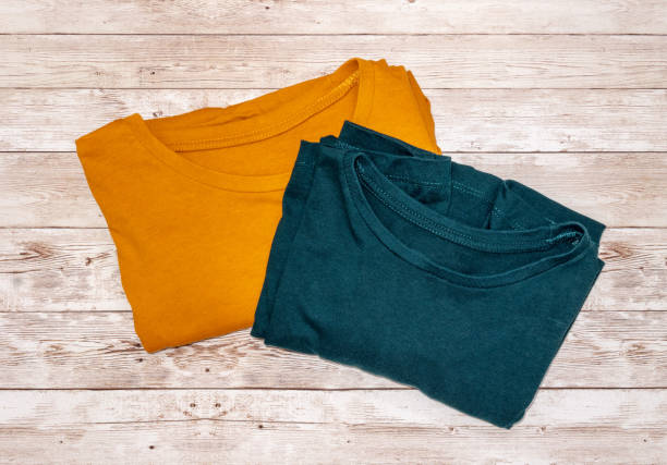 istock Folded orange and teal t-shirt on a wooden surface 957713070