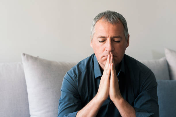 Mature man with eyes closed and hands clasped