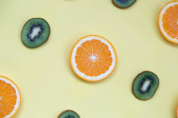 istock Kiwi and orange on tellow background 957729770