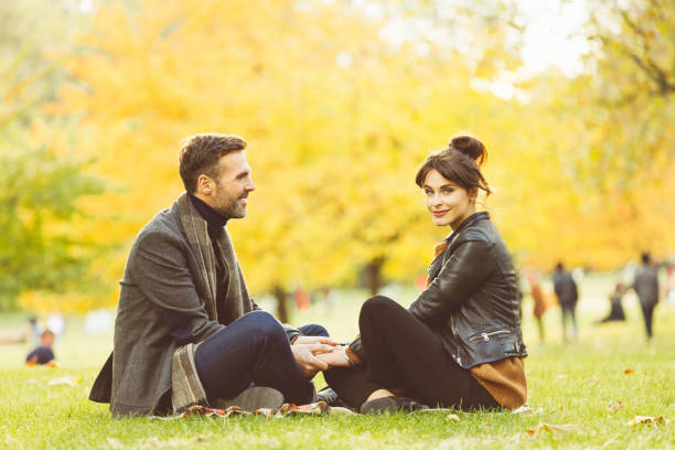 istock Couple sitting at public park on autumn weekend 957736998