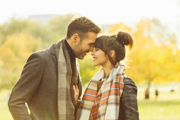 Happy couple standing face to face in the park. Autumn season.