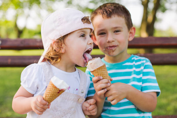 chłopiec dzieli lody ze swoją siostrą - park posing family outdoors zdjęcia i obrazy z banku zdjęć