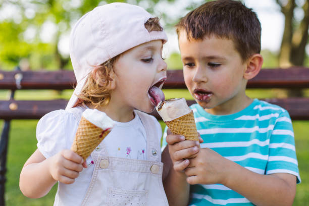 niño compartir el helado con su hermana - ice cream licking little boys ice cream cone fotografías e imágenes de stock