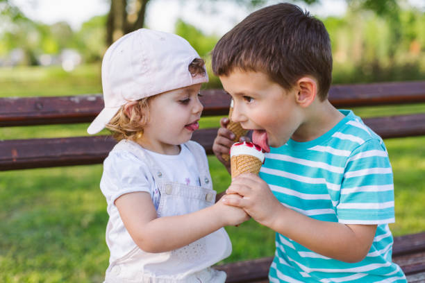 chica comparte su helado con hermano - ice cream licking little boys ice cream cone fotografías e imágenes de stock