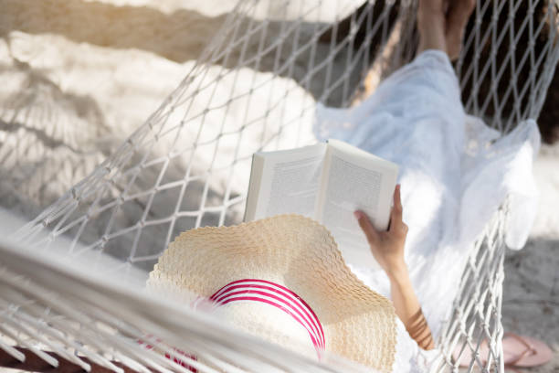 istock High Angle View Of Woman Reading Book While Leaning In Hammock 957758852