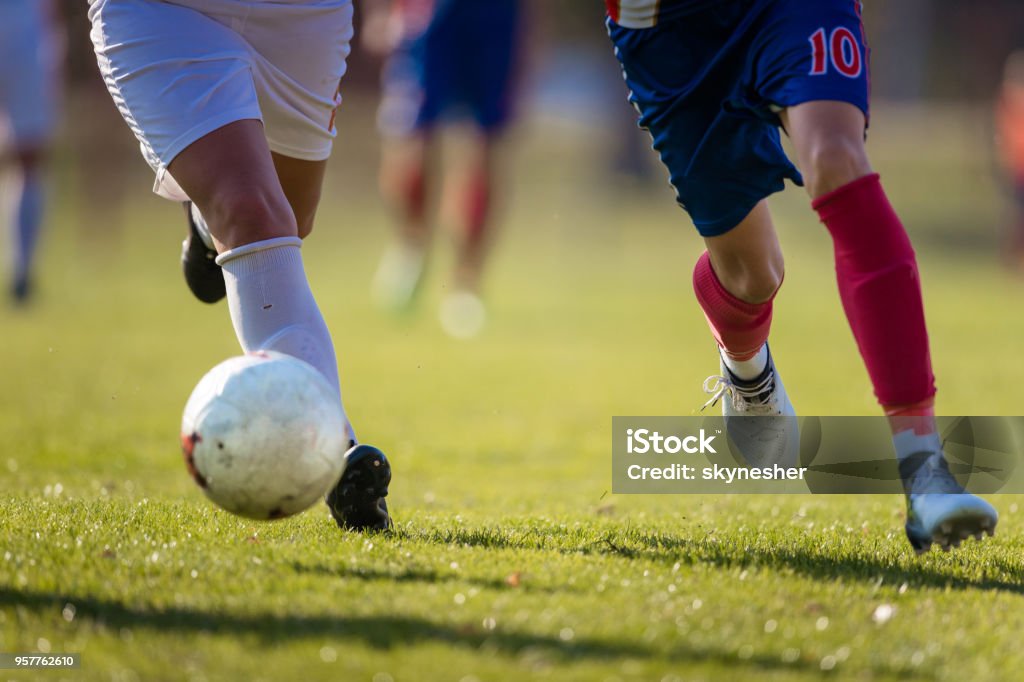 Two unrecognizable soccer players running with a ball on a match. Unrecognizable female soccer players running with a ball during a match on playing field. Copy space. Soccer Stock Photo