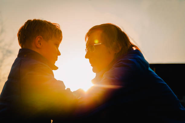 istock father and son silhouettes at sunset, parenting concept 957763610
