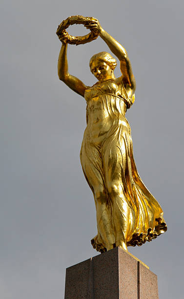 St. Petersburg, Russia. August 27, 2016: The vast grounds around Peterhof Palace are dotted with animated, including many gold colored, Baroque sculptures, oftentimes around a large fountain group, and depict mythological gods and goddesses, as well as historic figures. The figures are enlivened when the fountains are switched on. Shown here: a sculpture of a Greek/Roman goddess.